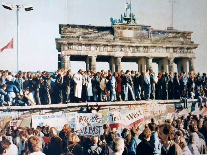 Civilians climbing and dismantling the Berlin Wall after its fall in November 1989